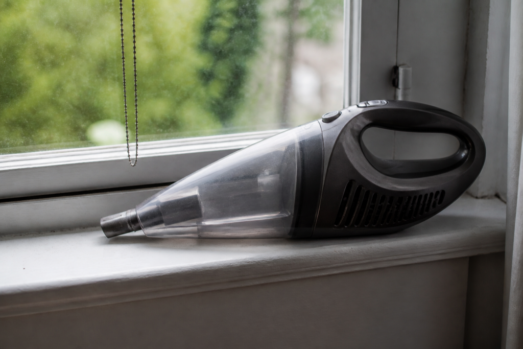 Aspirateur gris pose sur un rebord de fenetre blanc
