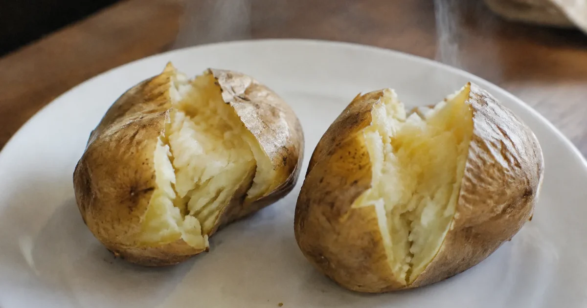 Deux patates fendues fumantes posees sur assiette blanche