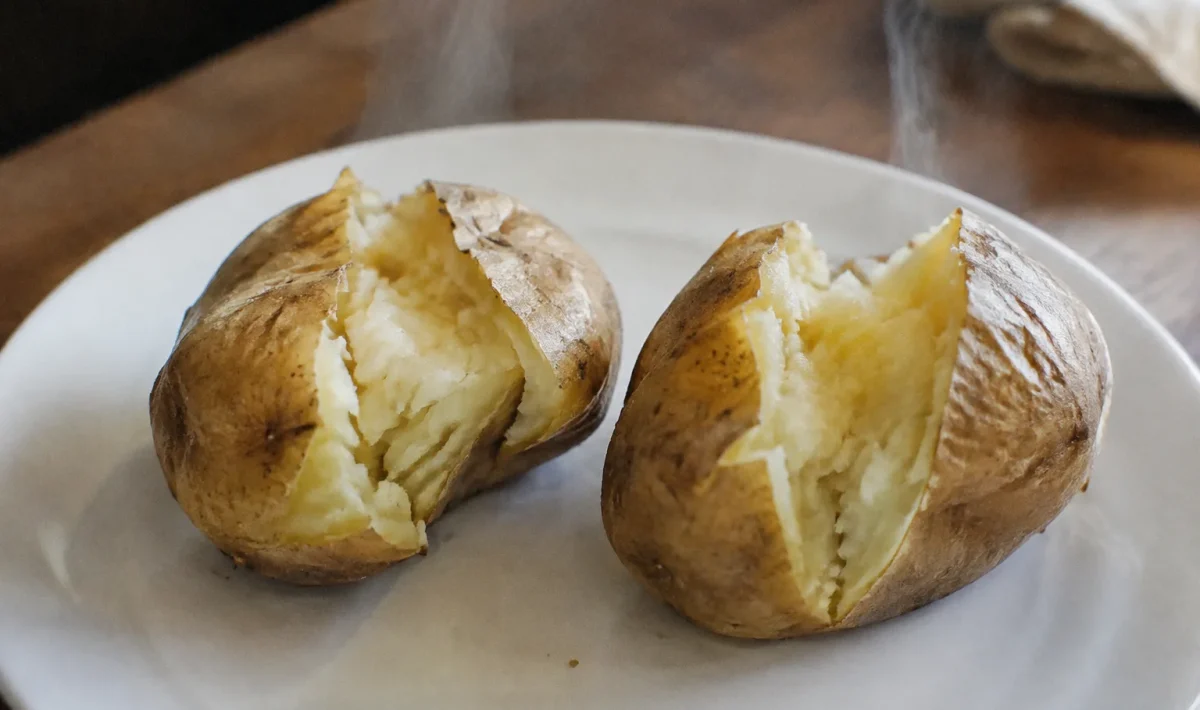 Deux patates fendues fumantes posees sur assiette blanche