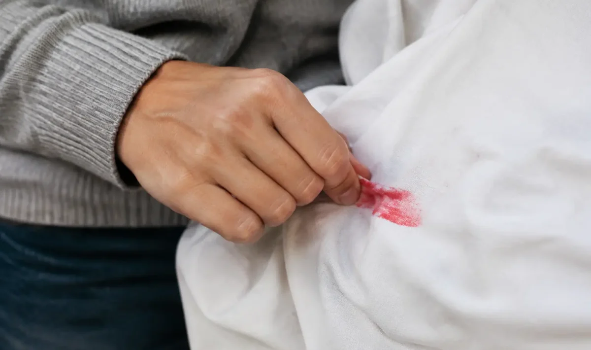 Main gantee frottant marque rouge sur tissu blanc