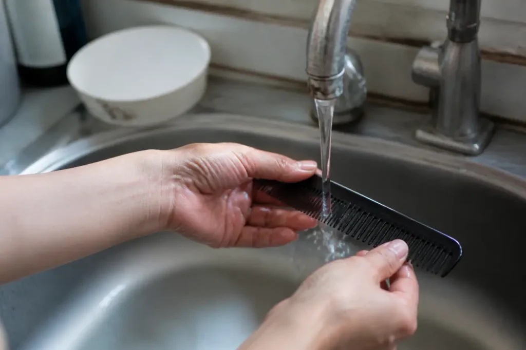 Main nettoyant un peigne sous l eau du robinet