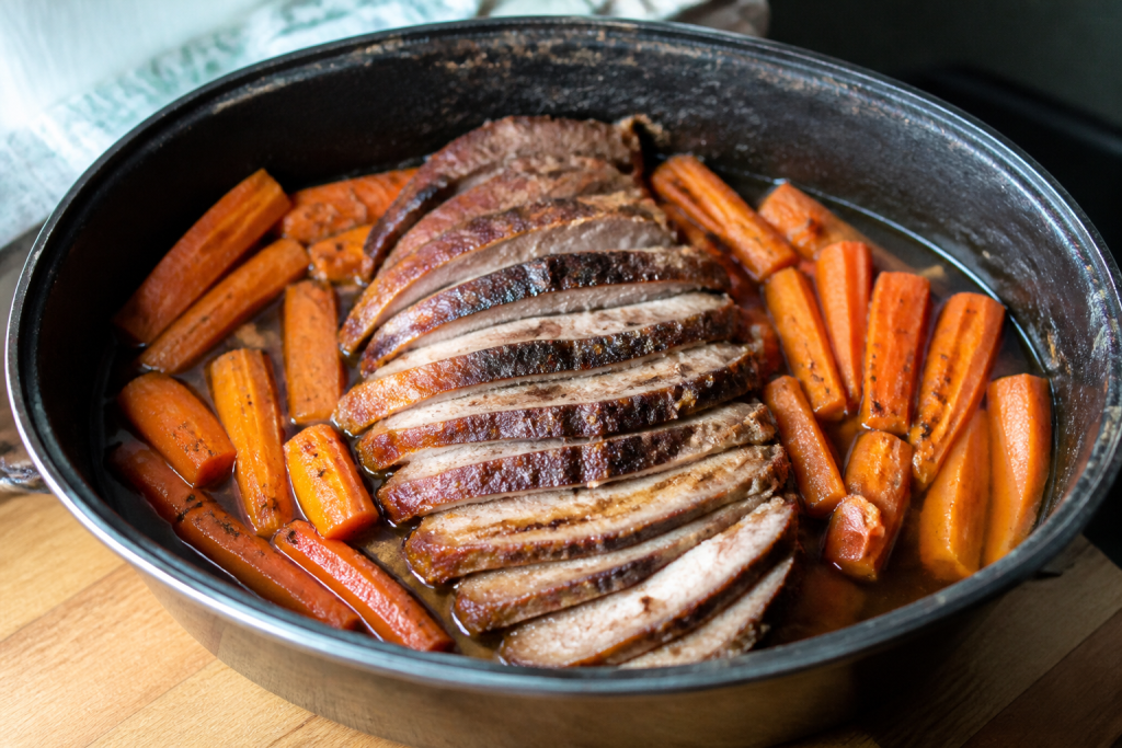 Viande tranchee entouree de carottes dans un plat chaud